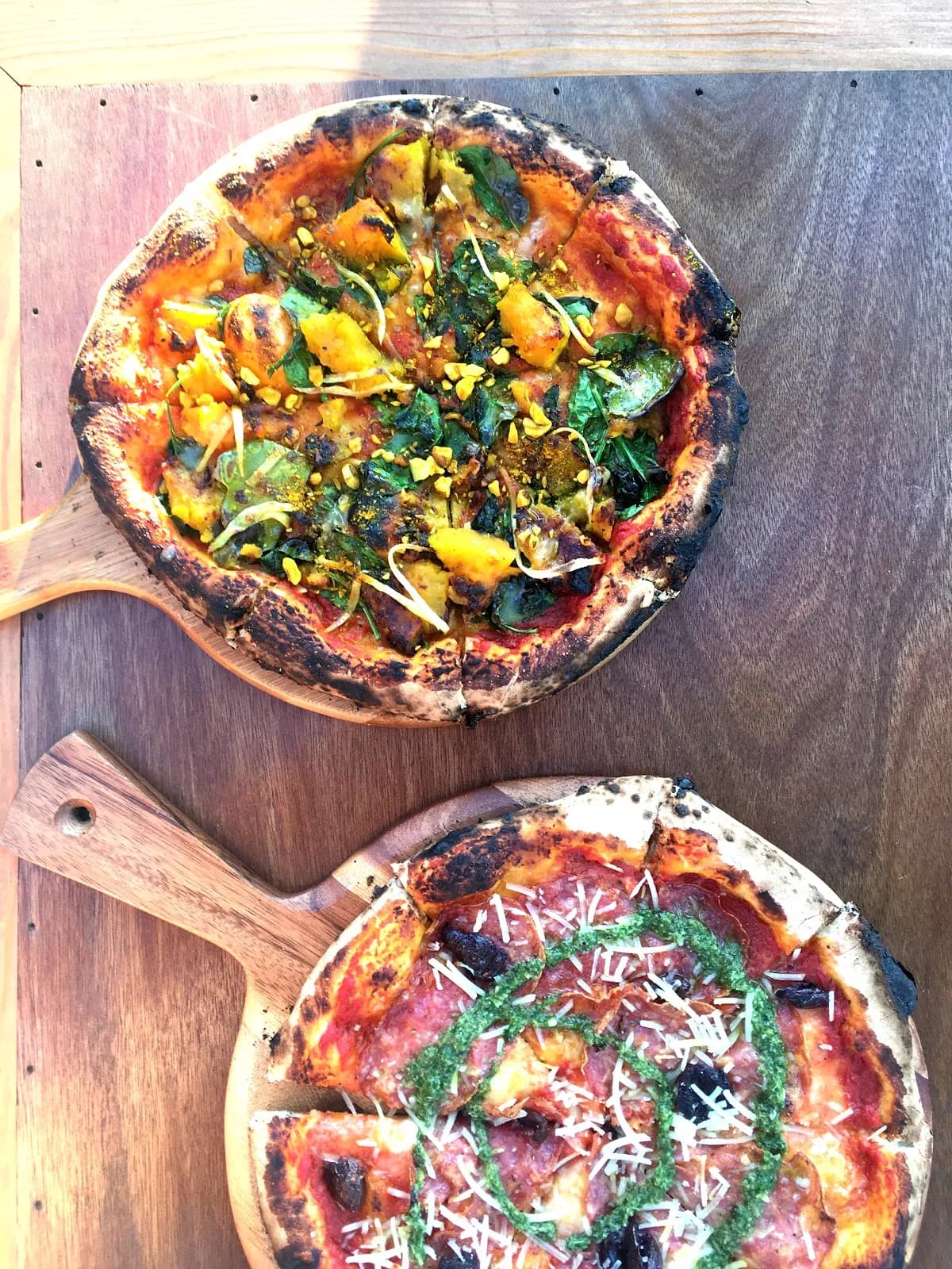 Two artisan pizzas with roast pumpkin and fresh herbs