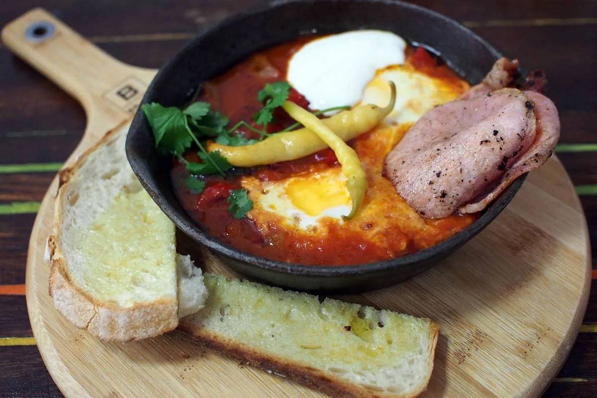 Shakshuka baked eggs in a cast iron skillet with toasted bread